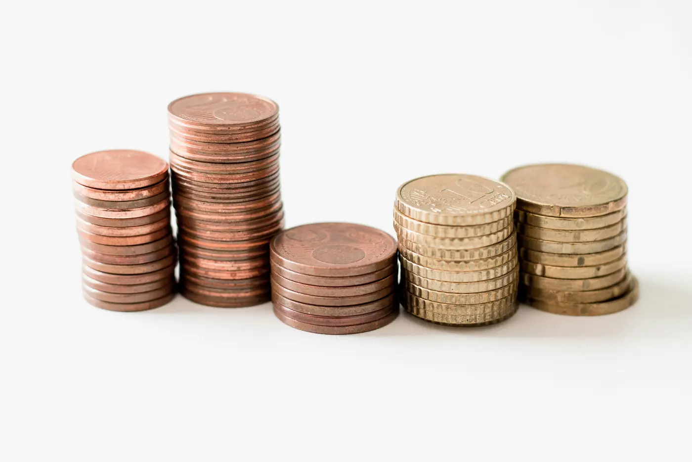 Stacks of copper and gold coins on a white surface