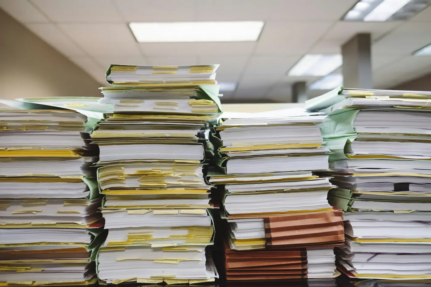 Tall stacks of paper files and documents in an office