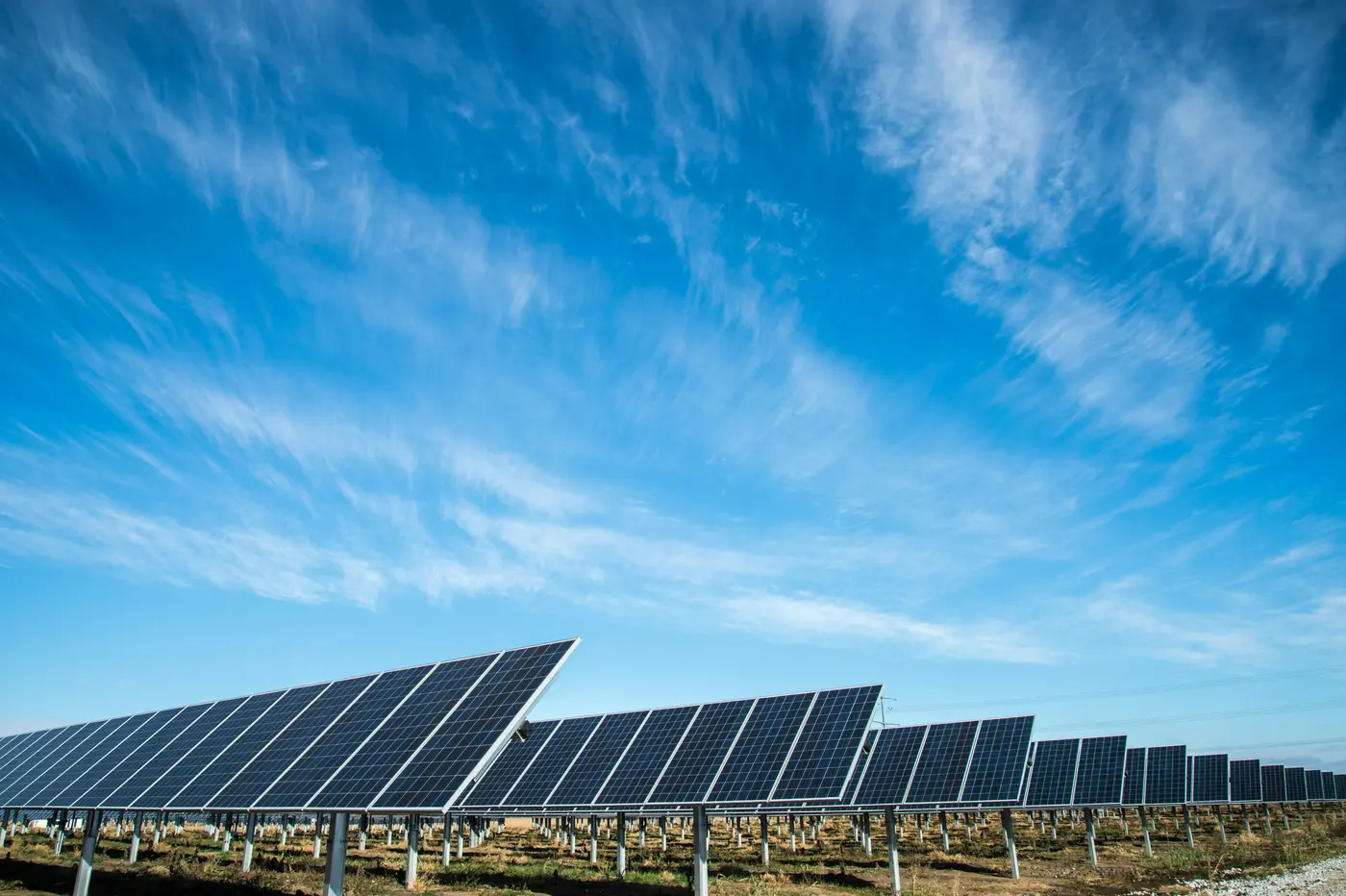 Rows of ground-mounted solar panels under a blue sky